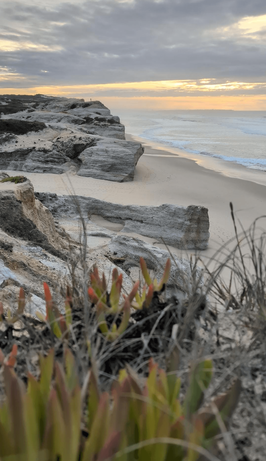 Atlantic waves, a sandy beach and coastal cliffs at sunset.