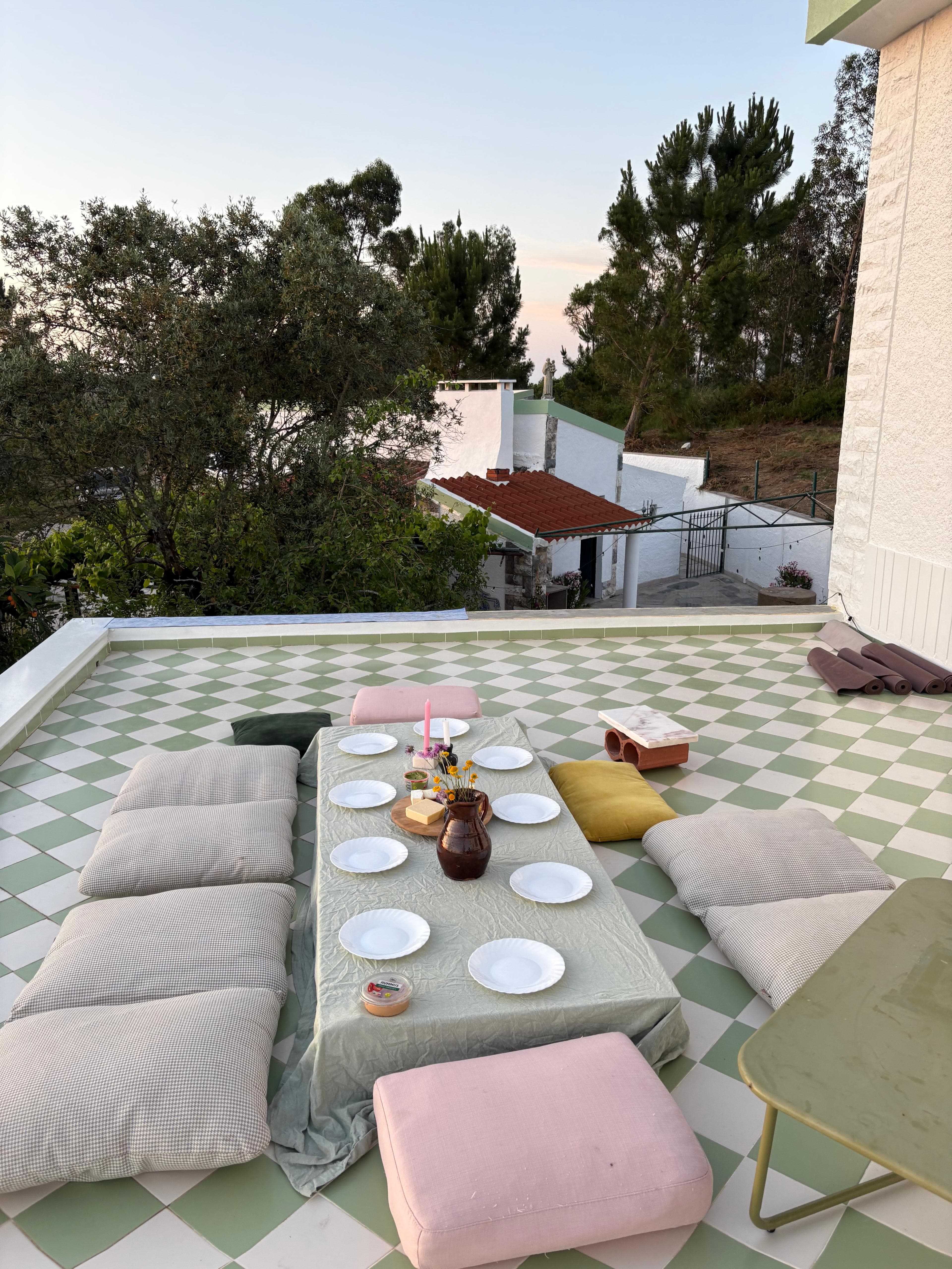 A shared terrace table set between trees and green tiles.